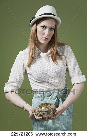 Portrait of a woman holding a golden egg in the bird's nest View Large Photo Image Stock Photograph - Portrait of a woman holding a golden egg in the bird's nest. Fotosearch
