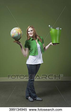 Stock Photography - Portrait of a woman holding a recycling bin and a globe. Fotosearch