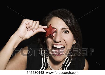 Portrait of a woman holding a star shape in front of her eye View Large Photo Image Stock Photo - Portrait of a woman holding a star shape in front of her eye. Fotosearch