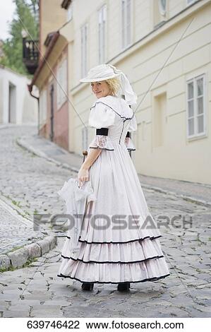 Stock Image - Portrait of a woman standing on a street and smiling. Fotosearch