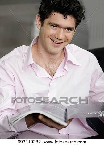 Portrait of a young man holding a magazine and smiling View Large Photo Image Stock Image - Portrait of a young man holding a magazine and smiling. Fotosearch