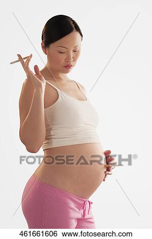 Pregnant woman holding a cigarette on her abdomen View Large Photo Image Stock Photograph - Pregnant woman holding a cigarette on her abdomen. Fotosearch