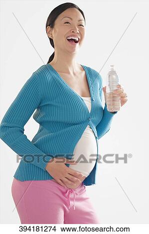 Pregnant woman laughing and touching her abdomen View Large Photo Image Picture - Pregnant woman laughing and touching her abdomen. Fotosearch