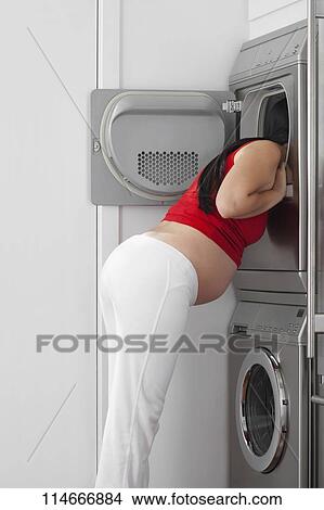 Pregnant woman looking into a washing machine View Large Photo Image Picture - Pregnant woman looking into a washing machine. Fotosearch