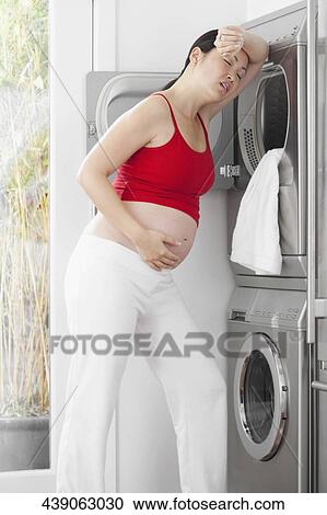 Pregnant woman looking tired in front of a washing machine View Large Photo Image Stock Image - Pregnant woman looking tired in front of a washing machine. Fotosearch