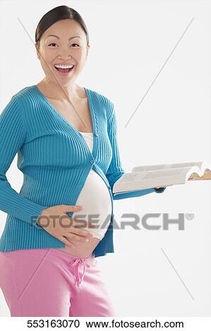 Pregnant woman smiling and holding a book View Large Photo Image Stock Image - Pregnant woman smiling and holding a book. Fotosearch