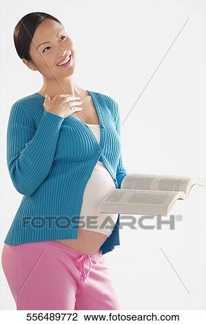 Pregnant woman smiling and holding a book View Large Photo Image Stock Image - Pregnant woman smiling and holding a book. Fotosearch
