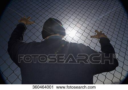 Prisoner clinging to a chainlink fence View Large Photo Image Stock Image - Prisoner clinging to a chainlink fence. Fotosearch
