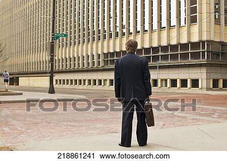 Rear view of a businessman standing with a briefcase View Large Photo Image Stock Image - Rear view of a businessman standing with a briefcase. Fotosearch