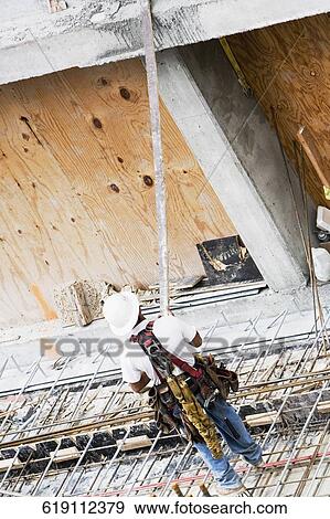 Rear view of a construction worker working at a construction site View Large Photo Image Stock Photo - Rear view of a construction worker working at a construction site. Fotosearch