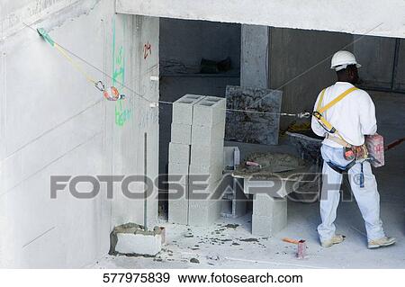 Rear view of a construction worker tied to a harness View Large Photo Image Stock Photo - Rear view of a construction worker tied to a harness. Fotosearch