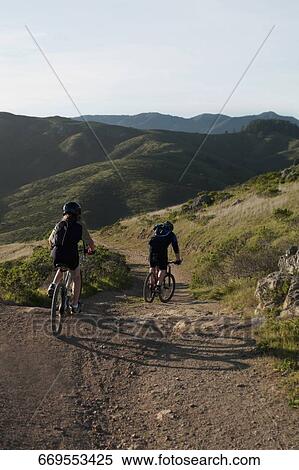 Stock Photography - Rear view of a couple mountain biking. Fotosearch