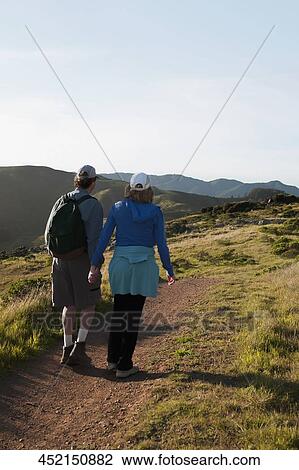 Stock Image - Rear view of a couple walking on a hiking trail. Fotosearch