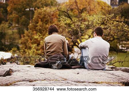 Rear view of a man and a woman sitting on a rock in a park, New York City, New York State, USA View Large Photo Image Picture - Rear view of a man and a woman sitting on a rock in a park, New York City, New York State, USA. Fotosearch