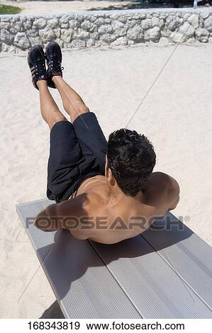 Rear view of a man exercising on the beach View Large Photo Image Stock Photo - Rear view of a man exercising on the beach. Fotosearch