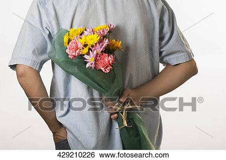 Stock Photograph - Rear view of a man holding flowers. Fotosearch
