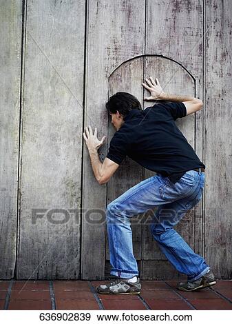 Rear view of a man peeking through a gate View Large Photo Image Stock Photo - Rear view of a man peeking through a gate. Fotosearch