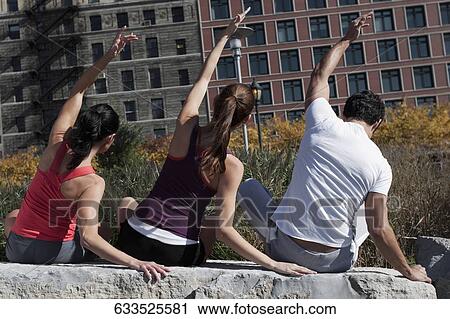 Rear view of a man with two women exercising on a rock View Large Photo Image Stock Image - Rear view of a man with two women exercising on a rock. Fotosearch