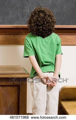 Rear view of a schoolboy standing in front of a blackboard View Large Photo Image Stock Photo - Rear view of a schoolboy standing in front of a blackboard. Fotosearch