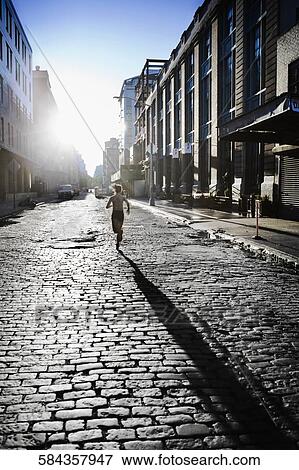 Rear view of a woman jogging in the street View Large Photo Image Stock Photo - Rear view of a woman jogging in the street. Fotosearch