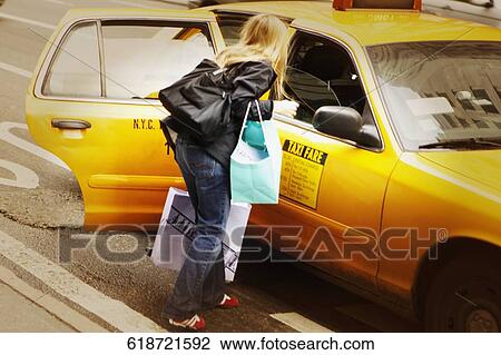 Rear view of a woman standing near a yellow taxi View Large Photo Image Stock Image - Rear view of a woman standing near a yellow taxi. Fotosearch