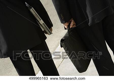 Rear view of two businessmen standing together View Large Photo Image Stock Image - Rear view of two businessmen standing together. Fotosearch