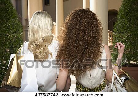 Stock Image - Rear view of two women holding shopping bags, Biltmore Hotel, Coral Gables, Florida, USA. Fotosearch