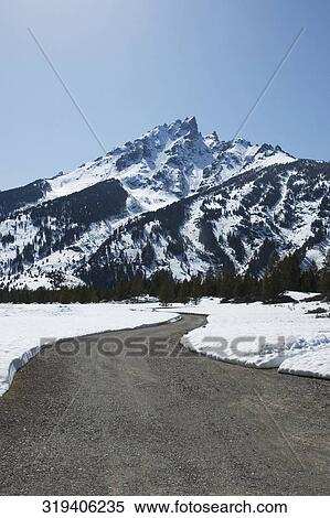 Stock Photography - Road passing through a snow covered landscape, Grand Teton National Park, Wyoming, USA. Fotosearch