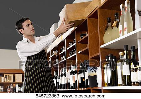 Sales clerk arranging wine bottles in a bar View Large Photo Image Stock Image - Sales clerk arranging wine bottles in a bar. Fotosearch