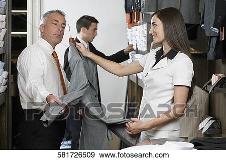 Sales clerk assisting a customer in the clothing store View Large Photo Image Stock Photo - Sales clerk assisting a customer in the clothing store. Fotosearch