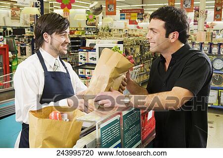 Sales clerk giving a grocery bag to a costumer in a supermarket View Large Photo Image Stock Image - Sales clerk giving a grocery bag to a costumer in a supermarket. Fotosearch
