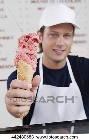 Sales clerk giving an ice cream cone in an ice cream parlor View Large Photo Image Stock Image - Sales clerk giving an ice cream cone in an ice cream parlor. Fotosearch