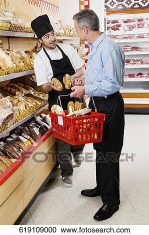Sales clerk giving breads to a man in a supermarket View Large Photo Image Stock Image - Sales clerk giving breads to a man in a supermarket. Fotosearch