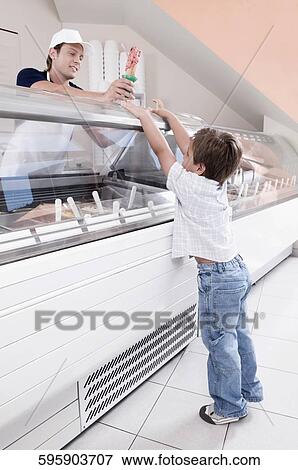 Stock Photo - Sales clerk giving ice cream to a boy in an ice cream parlor. Fotosearch