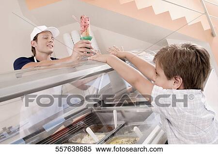 Stock Photography - Sales clerk giving ice cream to a boy in an ice cream parlor. Fotosearch