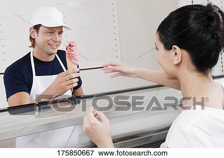 Sales clerk giving ice cream to a customer in an ice cream parlor View Large Photo Image Stock Photo - Sales clerk giving ice cream to a customer in an ice cream parlor. Fotosearch