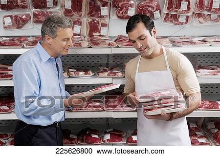 Sales clerk giving meat to a man in a supermarket View Large Photo Image Stock Image - Sales clerk giving meat to a man in a supermarket. Fotosearch