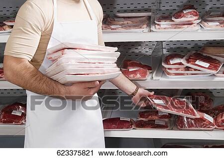 Sales clerk holding a stack of meat in a supermarket View Large Photo Image Stock Image - Sales clerk holding a stack of meat in a supermarket. Fotosearch