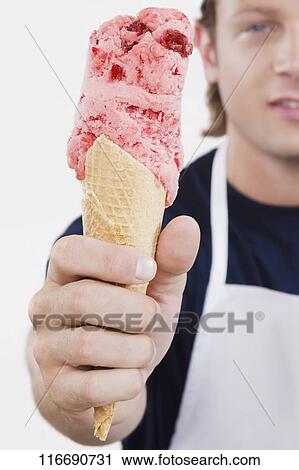 Sales clerk holding an ice cream cone in an ice cream parlor View Large Photo Image Stock Image - Sales clerk holding an ice cream cone in an ice cream parlor. Fotosearch