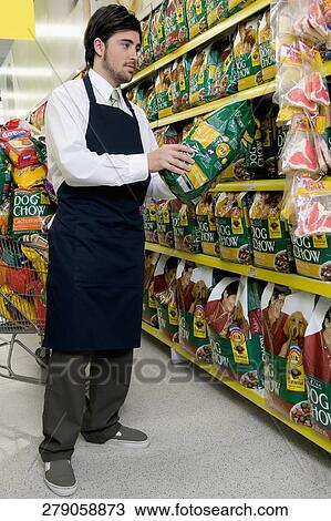 Sales clerk holding dog food in a supermarket View Large Photo Image Stock Image - Sales clerk holding dog food in a supermarket. Fotosearch