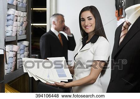 Stock Photo - Sales clerk holding fabric swatches in a clothing store. Fotosearch
