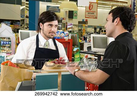 Sales clerk selling products to a costumer in a supermarket View Large Photo Image Stock Image - Sales clerk selling products to a costumer in a supermarket. Fotosearch