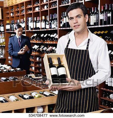 Sales clerk showing a crate of wine bottles View Large Photo Image Stock Photo - Sales clerk showing a crate of wine bottles. Fotosearch