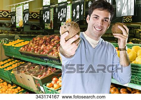 Stock Photo - Sales clerk showing coconuts. Fotosearch