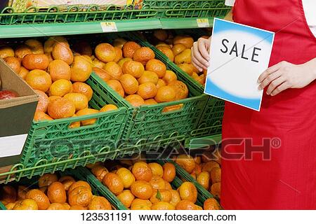 Sales clerk showing placard near crates of oranges View Large Photo Image Stock Image - Sales clerk showing placard near crates of oranges. Fotosearch