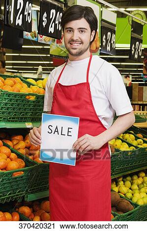 Salesman showing a Sale signboard in front of fruits' crates View Large Photo Image Stock Image - Salesman showing a Sale signboard in front of fruits' crates. Fotosearch