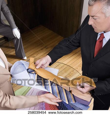 Saleswoman assisting a businessman in a clothing store View Large Photo Image Picture - Saleswoman assisting a businessman in a clothing store. Fotosearch