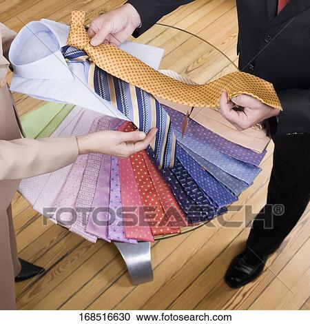 Saleswoman assisting a businessman in a clothing store View Large Photo Image Stock Image - Saleswoman assisting a businessman in a clothing store. Fotosearch