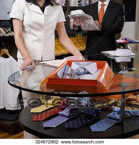 Saleswoman assisting a businessman in a clothing store View Large Photo Image Stock Image - Saleswoman assisting a businessman in a clothing store. Fotosearch