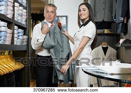 Saleswoman assisting a businessman in a clothing store View Large Photo Image Stock Photography - Saleswoman assisting a businessman in a clothing store. Fotosearch